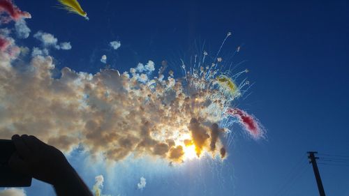 Low angle view of fireworks against blue sky