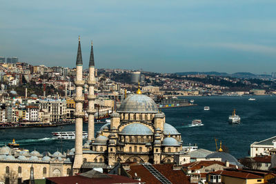 Mosque by lake against sky in city