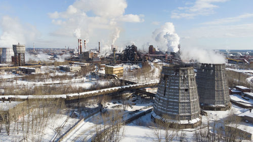 Smoke emitting from factory against sky