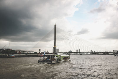 Rama viii bridge over chao phraya river against cloudy sky