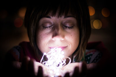 Close-up of woman holding fairy lights