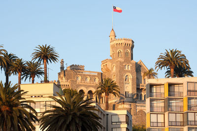 Low angle view of palm trees and buildings against sky