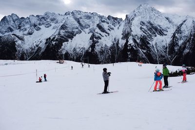 People skiing on snowcapped mountain against sky