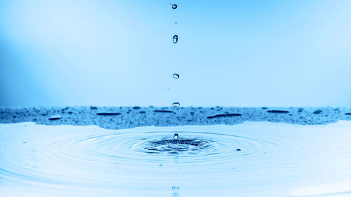 Close-up of drop falling on blue water
