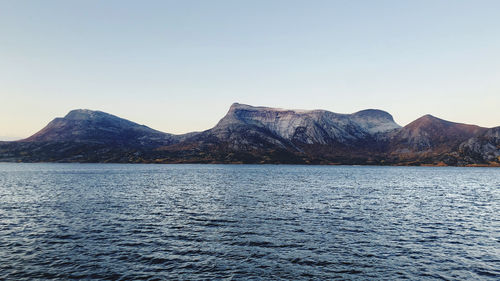 Scenic view of sea and mountains against clear sky