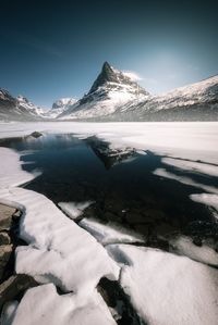 Scenic view of lake by snow mountains against sky