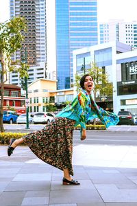 Woman smiling while standing against buildings in city