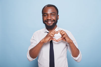 Portrait of young man standing against blue background