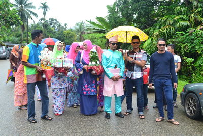 People with bridegroom standing on road during wedding ceremony