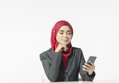 Mid adult man using smart phone against white background