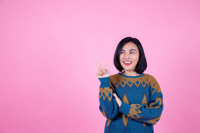 Portrait of smiling young woman against pink background