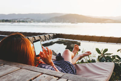 Woman using mobile phone while sitting on lounge chair