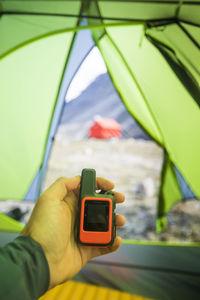 Man holds gps and satellite safety communication device in tent.