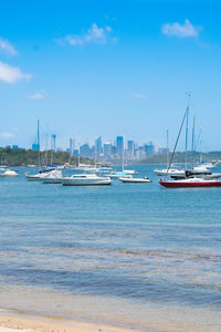 Sailboats moored at harbor against blue sky