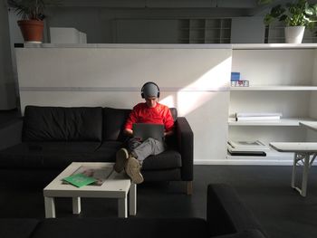 Man using laptop while resting on sofa at creative office