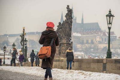 Rear view of people walking in city against sky