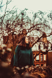 Woman sitting on plant against trees