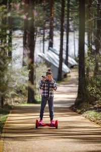 A girl rides a gyro scooter on a path in the forest