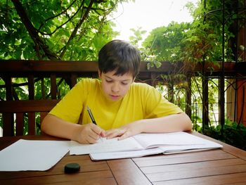 Boy studying at table in porch