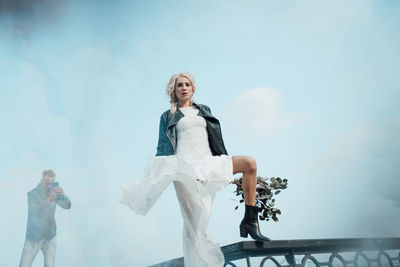 Low angle view of woman standing against sky