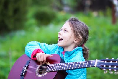 Cute girl playing guitar outdoors