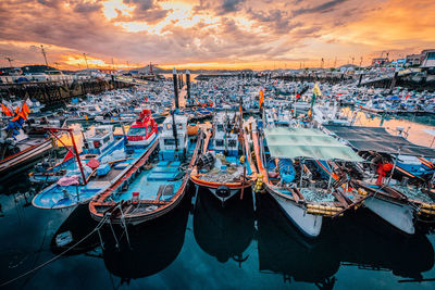 Boats moored at harbor in city against sky