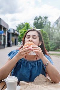 Portrait of young woman having food at street cafe