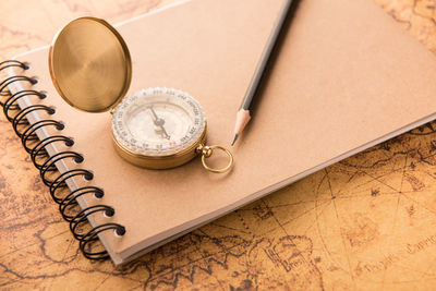 Close-up of note pad with navigational equipment and pencil on map