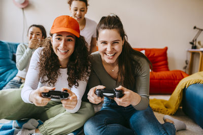 Young female friends enjoying video game at home