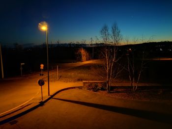Illuminated street light against sky at night