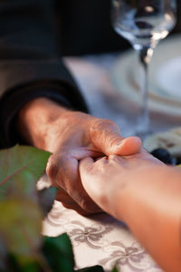 Old man and woman hold hands at a romantic dinner at a restaurant