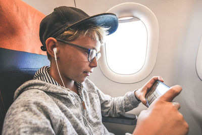 Cute boy using phone while sitting in airplane