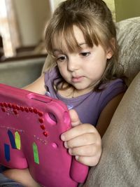 Close-up of girl playing video game on sofa at home