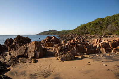 Rock formations on beach against clear sky