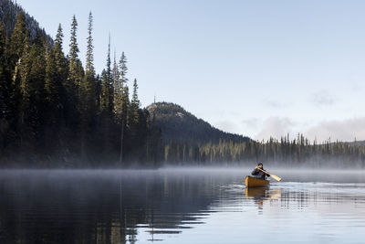 Man on boat in lake against trees