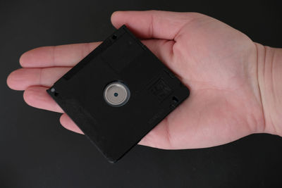 Close-up of hand holding camera over black background