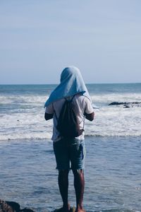 Rear view of man walking on beach against clear sky