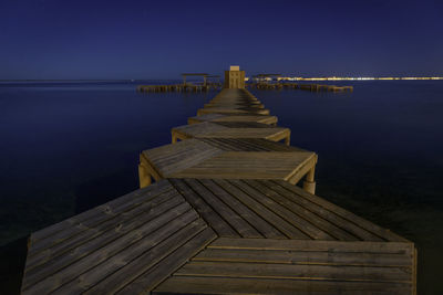 Pier over sea against clear sky at night