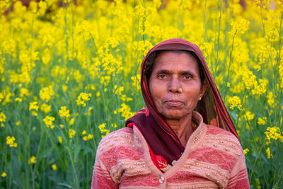 Portrait of senior woman with yellow flower in field