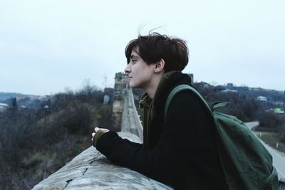 Side view of boy sitting against clear sky