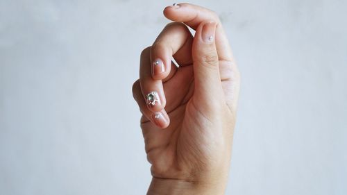 Cropped hand of woman with nail art against white background