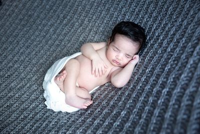 High angle view of baby girl sleeping on textile