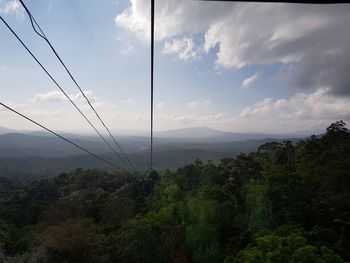 Overhead cable car over landscape against sky