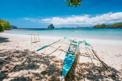 Outtrigger boat at beach against sky