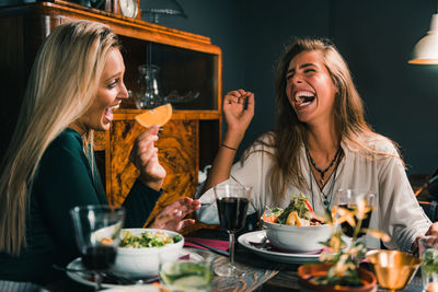 Happy young woman sitting at restaurant table