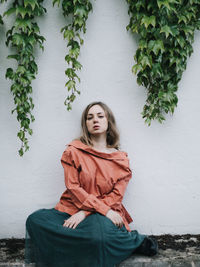 Portrait of young woman standing against wall