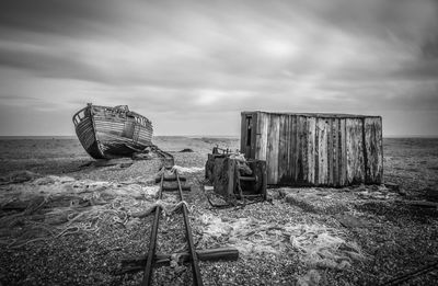 Abandoned wooden posts on beach against sky