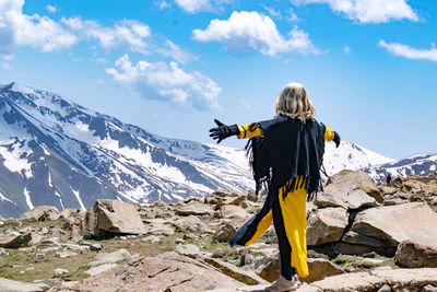 Rear view of woman standing on mountain against sky