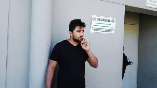 Young man standing against wall