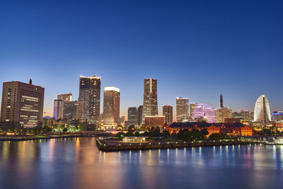 Buildings by river against clear sky